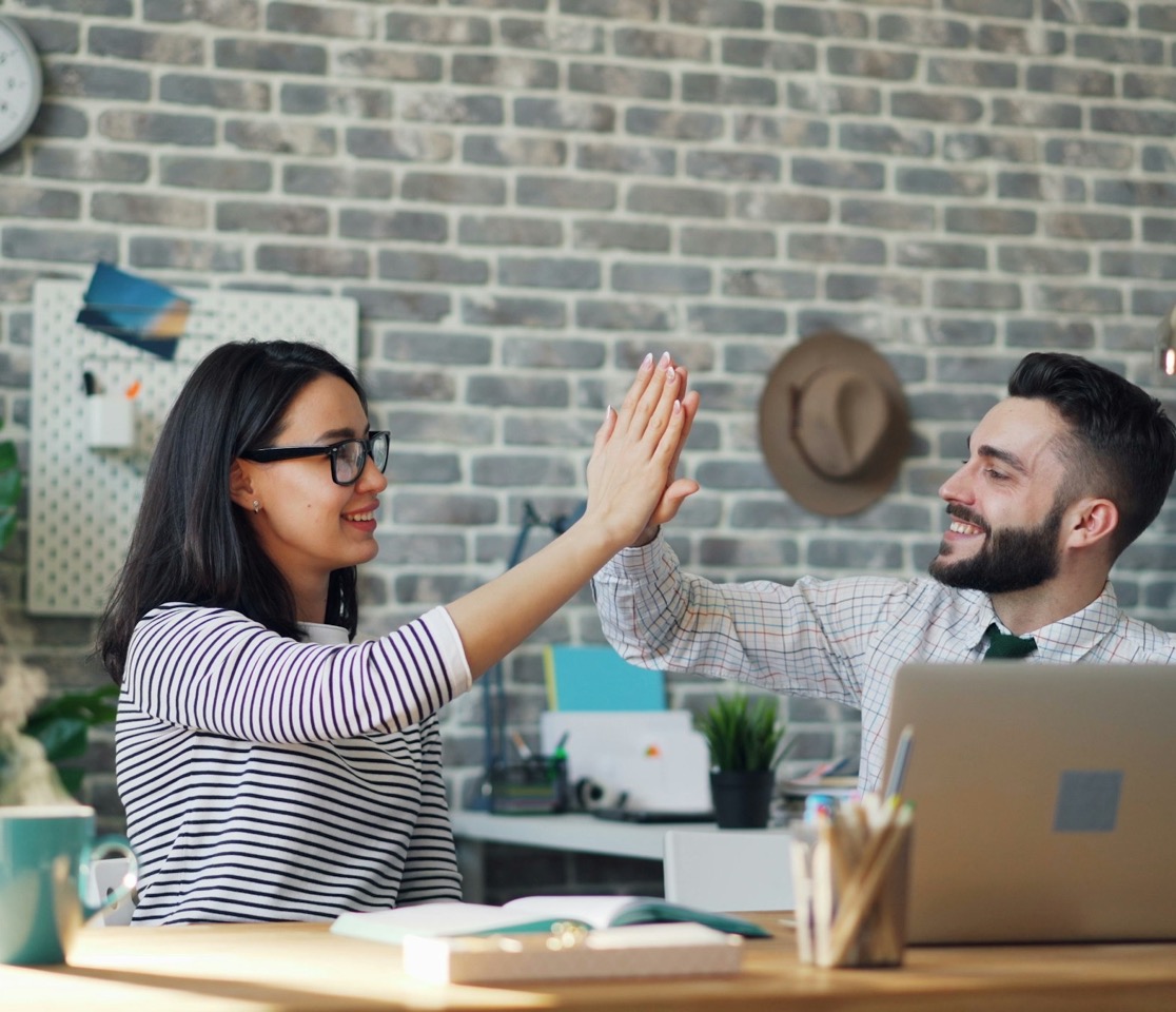 Two reseller partners celebrating a win with a high-five at their desks